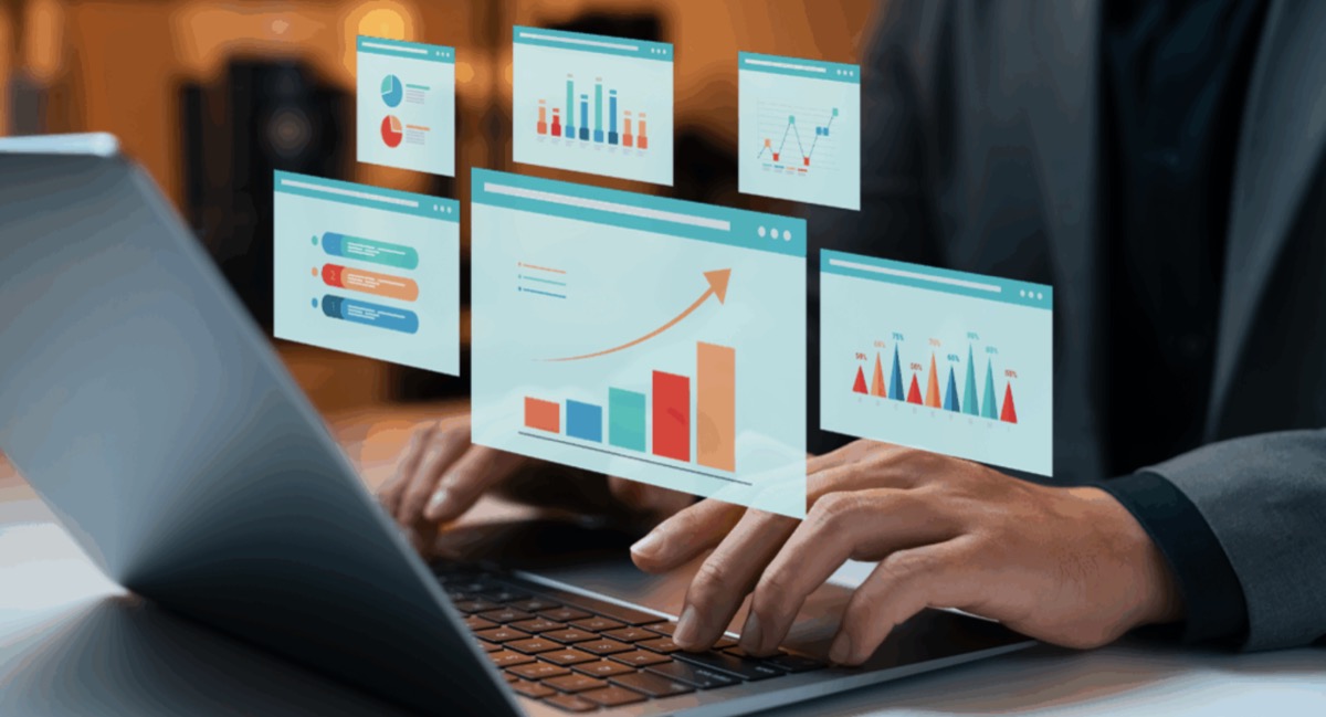 Person typing on a laptop with floating dashboards showing rankings, charts, and growth trends visualising LLM visibility as a composite of multiple AI search reporting layers