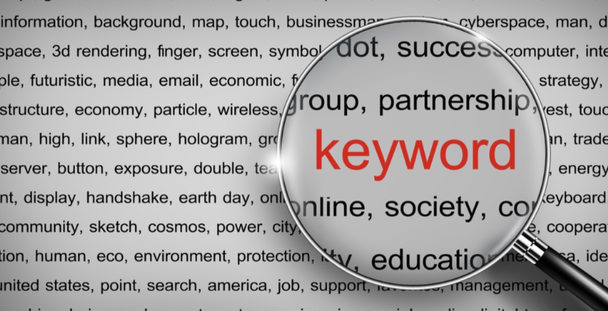 Magnifying glass enlarging the word keyword over a dense cloud of related terms like partnership, success, society, education, and online — illustrating competitor keyword discovery and gap analysis
